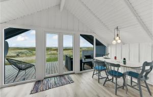 a dining room with a table and chairs and windows at Holiday Home Sdr Klitvej Hvide Sande Denm in Havrvig