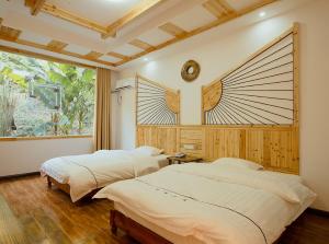 two beds in a room with a window at Hongfu Villa - Zhangjiajie National Forest Park West Gate in Zhangjiajie
