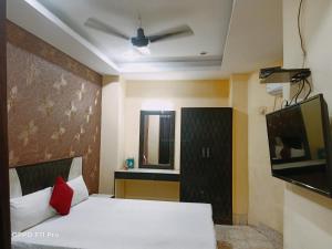 a bedroom with a white bed and a television at Hotel Ambassador Inn in Gwalior