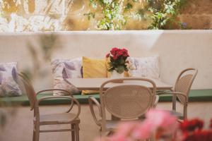 un tavolo e delle sedie con sopra un vaso di fiori di Maria Rosa Suites a Victoria