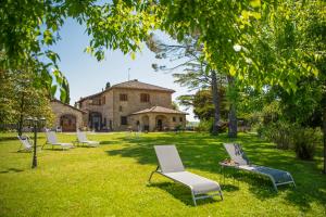 a group of chairs sitting in the grass in front of a building at Villa Egle Perugia in Cenerente