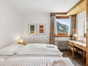 a bedroom with a bed and a desk and a window at Apartment Guardaval - Utoring-44 by Interhome in Davos