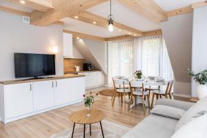 a kitchen and living room with a table and chairs at TatryTop Apartamenty Sabała in Zakopane