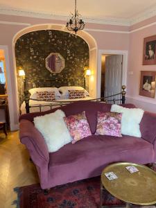 a living room with a purple couch and a bed at The Nest at Corbies Rest in Inverness