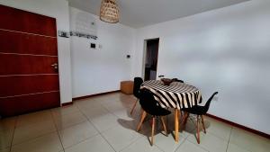 a dining room with a table and two black chairs at Departamento Cofico in Córdoba