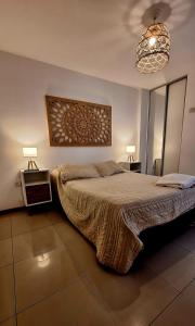 a bedroom with a bed and two lamps and a chandelier at Departamento Cofico in Cordoba