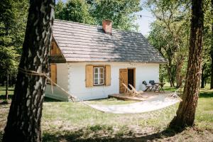 a small white house with a hammock in front of it at Sielsko in Lipsko-Polesie