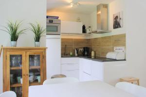 a kitchen with white cabinets and white appliances at Previnaireweg 19 in Callantsoog +7 photos