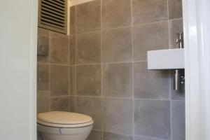 a bathroom with a toilet and a tiled wall at Previnaireweg 19 in Callantsoog
