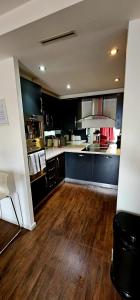 a large kitchen with black cabinets and wooden floors at Excel West Stays in London