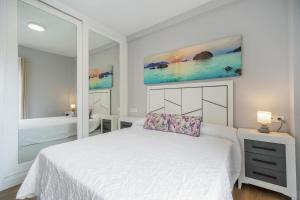 Dormitorio blanco con cama y espejo grande en Brisa marina, en El Puerto de Santa María 18 fotos más
