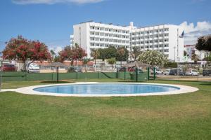 Una pequeña piscina en el césped con un edificio al fondo. en Brisa marina, en El Puerto de Santa María