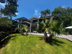 a house with palm trees in front of it at Villa Sand Golf by Carlon Luxury Rentals in Seignosse