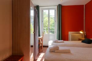 a bedroom with two beds with red walls and a window at Logis Hôtel Restaurant Le Louvre in Sault-de-Vaucluse