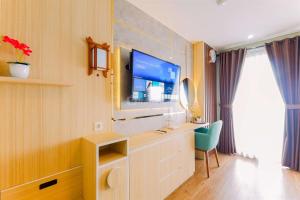 a room with a tv and a desk with a chair at Best Homey and Nice Studio at Royal Sentul Park Apartment By Travelio in Bogor