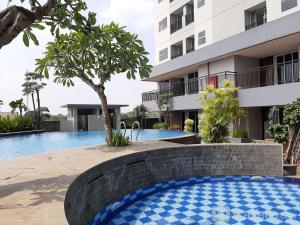 a swimming pool in front of a building at Comfort Minimalist Studio at Parkland Avenue Apartment By Travelio in Tangerang