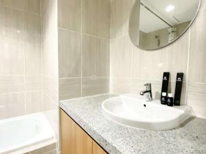 a white bathroom with a sink and a mirror at Best Homey 1BR at 25th Floor Vasanta Innopark Apartment By Travelio in Cikarang
