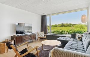 a living room with a blue couch and a large window at 3 Bedroom Cozy Home In Børkop in Børkop