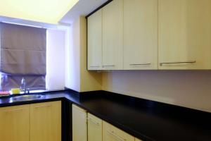 a kitchen with white cabinets and a black counter top at Modern Look 3BR at Apartment Braga City Walk By Travelio in Bandung