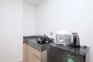 a kitchen with a sink and a coffee maker on a counter at New Furnished and Homey 2BR at Transpark Cibubur Apartment By Travelio in Depok