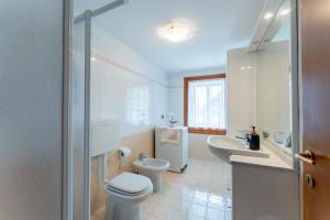 a white bathroom with a toilet and a sink at Grande Terrazzo - Zona Silenziosa e Strategica in Roana