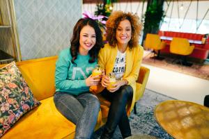 two women sitting on a couch holding drinks at Hotel ReeHorst in Ede