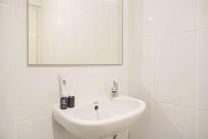 a white bathroom with a sink and a mirror at Great Choice and Homey 2BR at Tokyo Riverside PIK 2 Apartment By Travelio in Rawalembang +9 photos