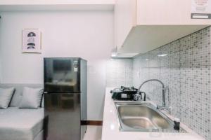 a small kitchen with a sink and a refrigerator at Well Furnished and Comfy 2BR at Royal Heights Apartment By Travelio in Bantarkamang +12 photos