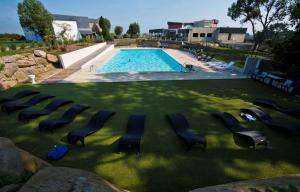 a group of chairs sitting in the grass near a swimming pool at Brit Hotel Golfhotel Saint Samson in Pleumeur-Bodou