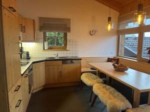 une cuisine avec des armoires en bois et une table avec des bancs dans l'établissement Schöneben Chalet Ferienwelt, à Wald im Pinzgau