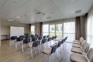 een vergaderzaal met stoelen en een whiteboard bij Brit Hotel Saint-Méen-le-Grand en Brocéliande in Saint-Onen-la-Chapelle
