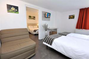 a hotel room with a bed and a chair at Brit Hotel Bosquet Carcassonne Cité in Carcassonne