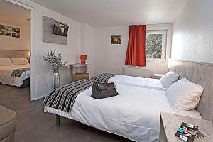 a bedroom with a large white bed and a window at Brit Hotel Bosquet Carcassonne Cité in Carcassonne