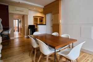 a dining room with a wooden table and white chairs at Old Lille charming duplex apartment in Lille