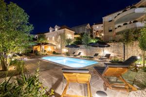 un cortile con piscina, sedie e un edificio di Grand Stone Casa Ciccarelli by Irundo a Pučišća