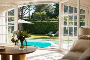 Una sala de estar con una gran puerta corrediza de vidrio que conduce a una piscina. en Villa avec piscine Domaine des Fées à 100 m plage, en Vaux-sur-Mer
