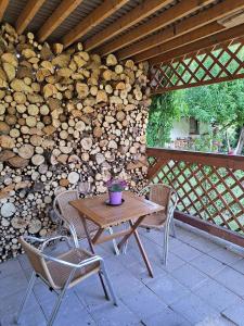 a wooden table and chairs on a patio with a pile of logs at Apartmán pod Javořicí in Studená