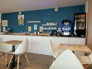 a restaurant with a counter with chairs and a table at Brit Hotel Les Alizes in Pornic