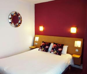 a bedroom with a white bed with two pillows at Brit Hotel Hermitage in Royan