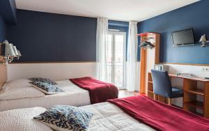a bedroom with two beds and a desk with a chair at Brit Hotel de Paris Saint-Jean-de-Luz in Saint-Jean-de-Luz