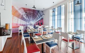 a restaurant with white tables and chairs and a mural at Brit Hotel de Paris Saint-Jean-de-Luz in Saint-Jean-de-Luz