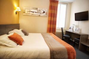 a hotel room with a bed and a desk and a window at Brit Hotel Le Surcouf in Saint Malo