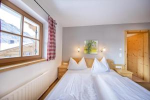 a bedroom with a large white bed with a window at Schöneben Chalet MilKa in Wald im Pinzgau +31 photos