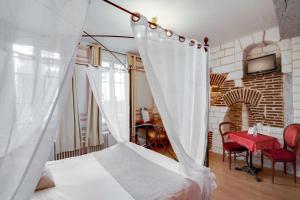 a bedroom with a white canopy bed and a table at Brit Hotel Comtes De Champagne - Troyes Centre Historique in Troyes