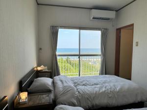 a bedroom with a bed and a large window at Kamizawa Villa - BBQ x オーシャンビュー in Kumiage