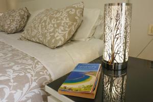 サンミゲル・デ・アボナにあるSweet home ocean golf resortのベッド横のテーブルにライトを載せた本