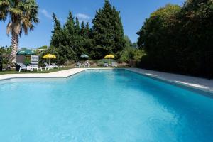 una grande piscina blu con sedie e ombrelloni di Brit Hotel Avignon Sud Le Calendal ad Avignone
