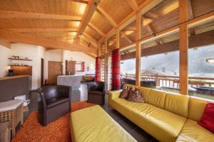 un salon avec un canapé jaune et une cuisine dans l'établissement Schöneben Chalet Anton, à Wald im Pinzgau