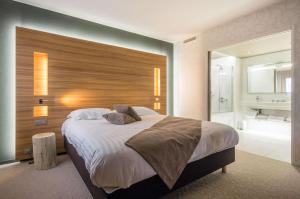 a bedroom with a large bed with a wooden headboard at Brit Hotel & Spa Saint Brieuc Plérin in Plérin