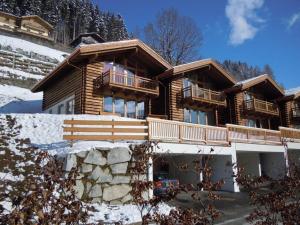 une grande maison en rondins avec de la neige au sol dans l'établissement Schöneben Haus Silberdistel, à Wald im Pinzgau